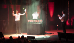 Två personer står på en scen och mellan dem är verisures nya logo